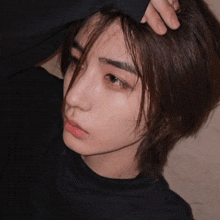 a close up of a person 's face with a hand on their hair