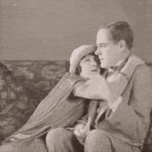 a woman in a hat is hugging a man on a floral couch