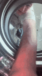 a person is putting clothes in a washing machine and smiling