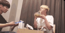 two young men are sitting at a table eating noodles and drinking tea .