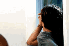 a woman is standing in front of a mirror looking at her hair .