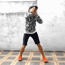a man wearing shorts and a hat is standing on a tiled floor .