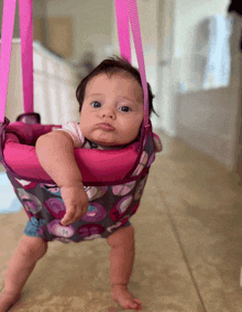 a baby in a pink and gray polka dot jumper