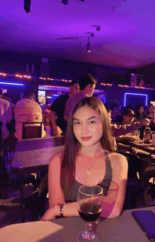 a woman sits at a table with a glass of wine in front of her
