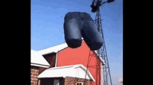 a giant inflatable butt is hanging from a windmill in front of a red barn .