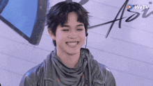 a young man wearing headphones and a scarf is smiling and looking at the camera .