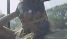 a woman sitting in a car looking out the window with her hand in her hair