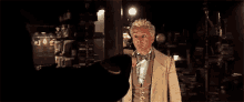 a man in a tuxedo and bow tie is standing in a dark room in a dark room .