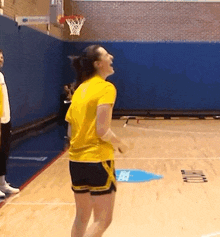a woman in a yellow shirt is jumping on a basketball court .