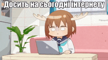 a girl with antlers is sitting at a table with an apple laptop