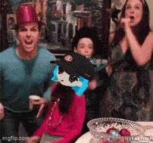 a group of people are gathered around a table with a picture of a girl with a hat on her head ..