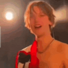 a man without a shirt is singing into a microphone on stage .