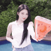 a woman in a white shirt is holding an inflatable watermelon