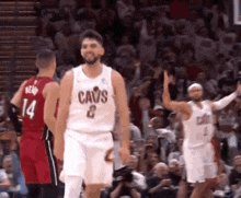 a basketball player wearing a cavs jersey is standing in front of a crowd .