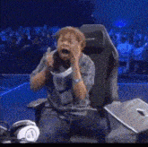 a man is sitting in a gaming chair with his mouth open and his hands on his face .