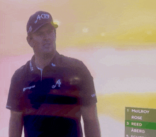 a man wearing an aces hat stands in front of a screen
