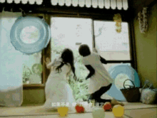 a man and a woman are playing with balloons in front of a window ..