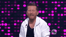 a man wearing a white jacket is laughing with his eyes closed .
