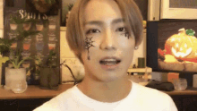 a man with a spider web on his face looks at the camera