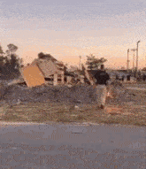 a man in a police uniform is walking in front of a pile of wood .