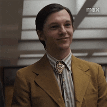 a man wearing a suit and tie with a max logo on the bottom