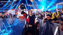 a woman is walking on a stage holding a championship belt .