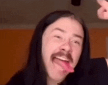 a man with a mustache is sticking his tongue out .
