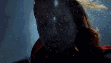 a woman in a superhero costume is swimming underwater and looking at the camera .
