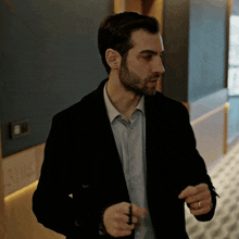 a man wearing a black jacket and a blue shirt has a ring on his finger