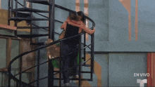 a couple hugging on a spiral staircase with the words en vivo on the bottom right