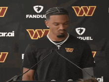 a man wearing a washington redskins shirt stands in front of a microphone
