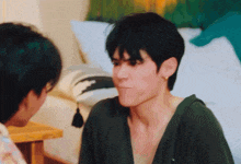 a man in a green shirt is making a funny face while another man looks on