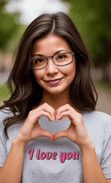 a woman wearing glasses makes a heart shape with her hands with the words i love you written on her shirt