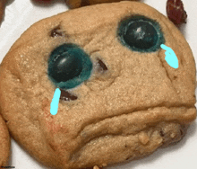 a cookie that looks like a sad face with blue eyes and a tear coming out of it