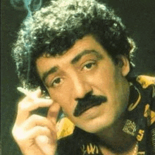 a man with a mustache is smoking a cigarette in a close up of his face .