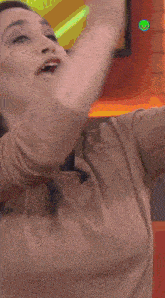 a woman is sitting on an orange couch with her hands in the air in front of a tv screen that says bateman