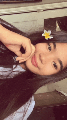 a girl with a flower in her hair is taking a selfie