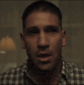 a close up of a man 's face with a plaid shirt
