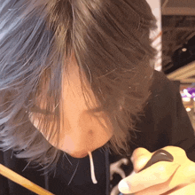 a close up of a person eating with chopsticks and a black shirt with the letter s on it