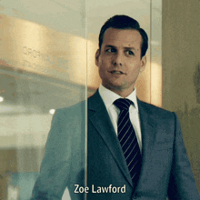 a man in a suit and tie is standing in front of a glass door and says zoe lawford