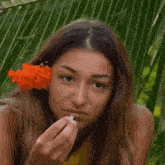 a woman is holding a flower in her hair and smiling