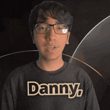 a man wearing glasses and a black shirt that says danny on it