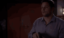 a man in a purple shirt is holding a ring in a box in his hand .