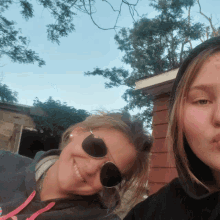 two girls wearing sunglasses pose for a picture together