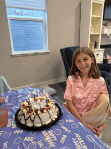 a girl sits at a table with a birthday cake