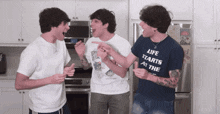 a man in a blue shirt that says life starts at the pointing at another man
