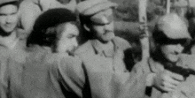 a black and white photo of a group of soldiers standing in a line .