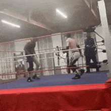 a man is standing in a boxing ring with another man standing behind him