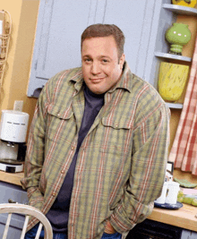 a man in a plaid shirt is standing in front of a coffee maker