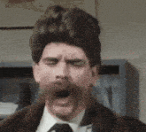 a man with a wig and a mustache is yawning with his mouth open .
